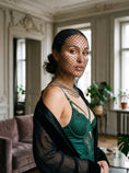 Cargar la imagen en la vista de la galería, Black diamond-net veil draping from crown to collarbone over an emerald satin slip in window light