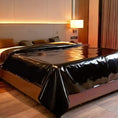 Load image into Gallery viewer, Black PVC play sheet spread over a bed in a dim bedroom