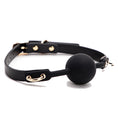 Load image into Gallery viewer, Angled view of the ball gag showing the gold studs beside the buckle and a D-ring tab