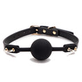 Load image into Gallery viewer, Black silicone ball gag on a slim black strap with gold pin buckle, gold D-rings and domed gold studs