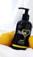 Cargar la imagen en la vista de la galería, Massage oil bottle resting on white bedding between two lemons