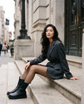 Cargar la imagen en la vista de la galería, XS micro-net fishnet tights with a grey wool blazer and tall boots on limestone steps in flat overcast light