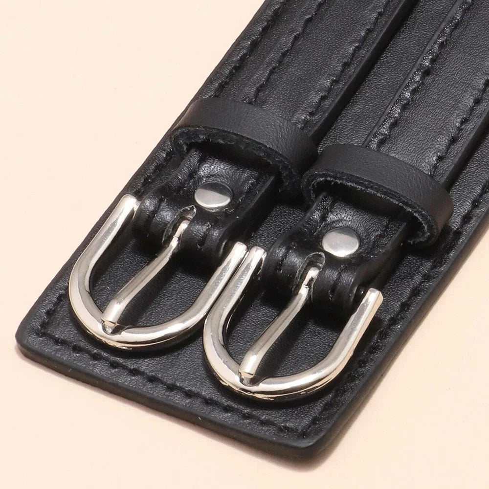 Close-up of the twin silver-tone buckles and stitched edge of the black cuff