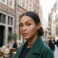 Cargar la imagen en la vista de la galería, Black rhinestone mesh face veil worn over the head and throat under a wool coat on a daylight street
