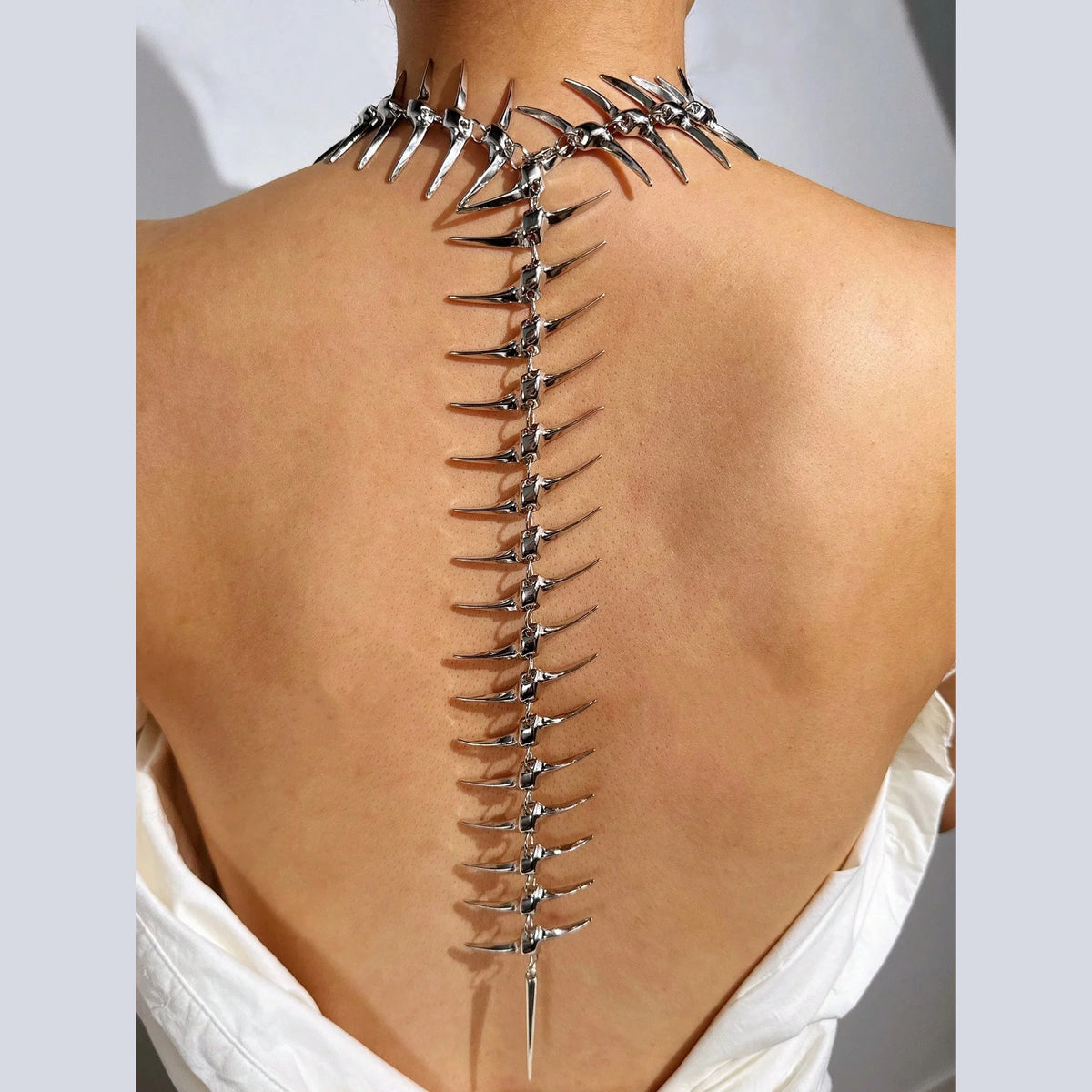 Spiked spine necklace worn down a bare back, collar fastened at the neck