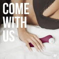 Cargar la imagen en la vista de la galería, The wine red stimulator on a bed beside a hand, showing its scale

