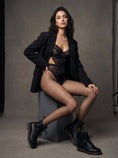 Cargar la imagen en la vista de la galería, Small grid fishnet tights with an open blazer against a grey studio backdrop, the net lit from the side
